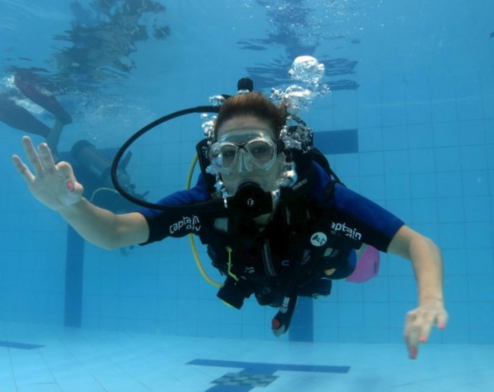 Aluna durante treinamento na piscina do curso de mergulho básico da Captain Dive.